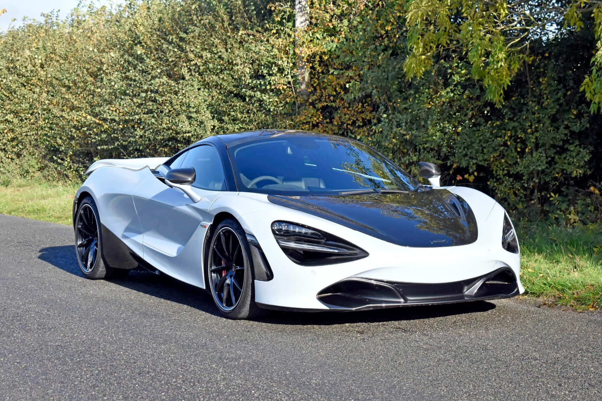 白色McLaren 720S跑車停在路上，背景有樹木。