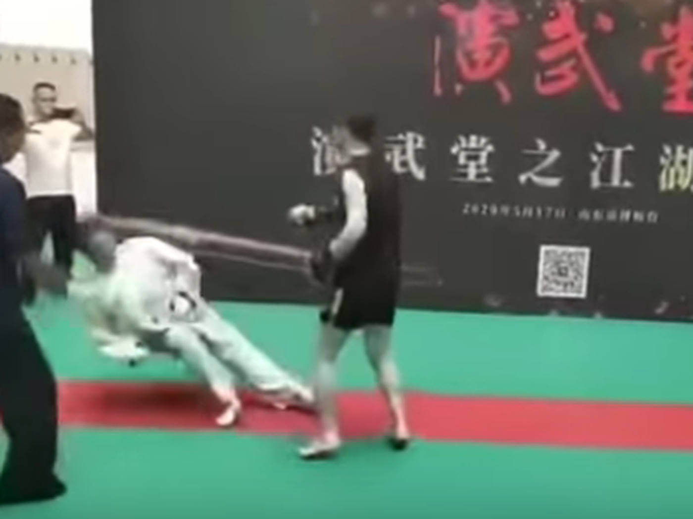 兩名拳手在彩色墊子上進行拳擊比賽，觀眾在觀看。
