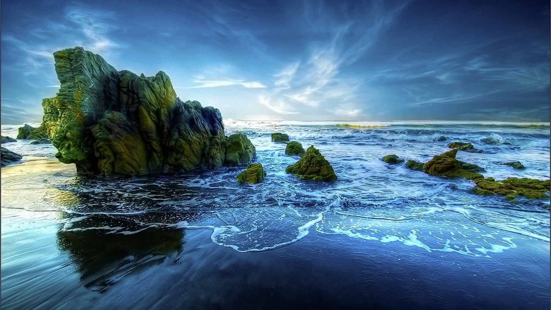 黃昏時分，苔蘚岩石與拍打黑暗海灘的海浪。