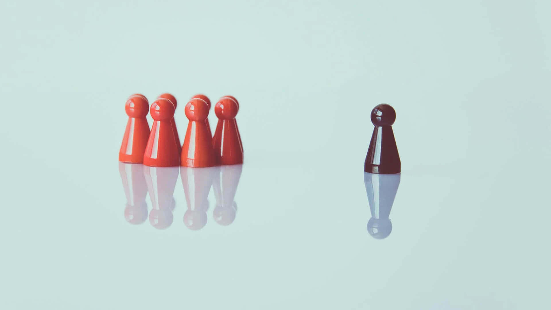 動態領導力概念 壁紙 — 一個深色兵卒獨立於一組紅色兵卒之外，站在反光的薄荷綠色表面上。