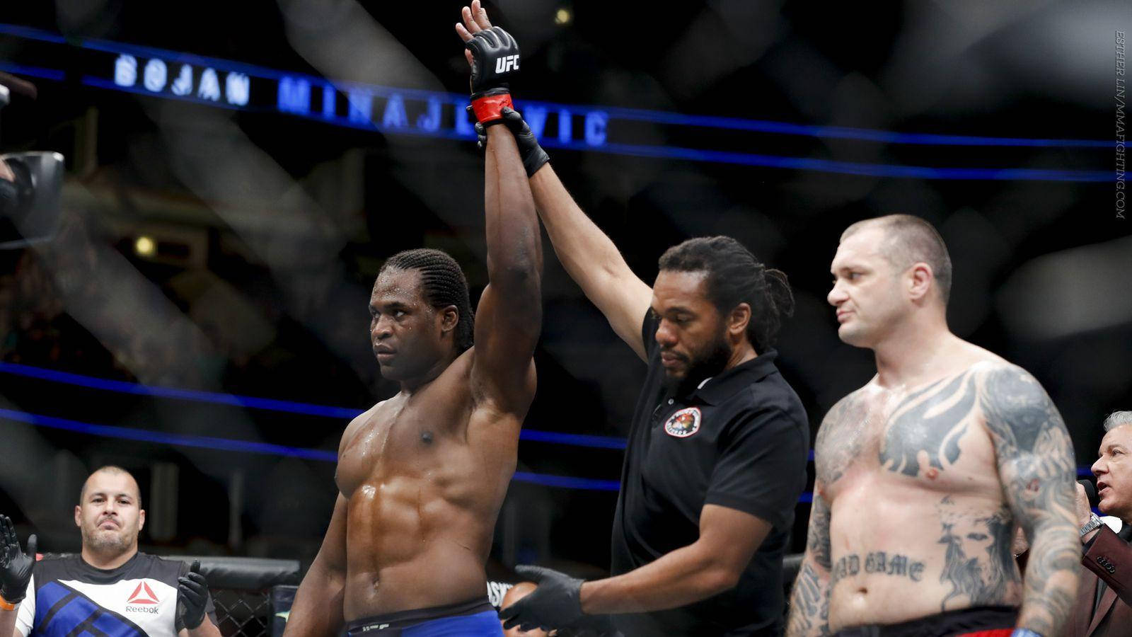 UFC拳手在八角籠內獲勝，裁判舉起他的手。