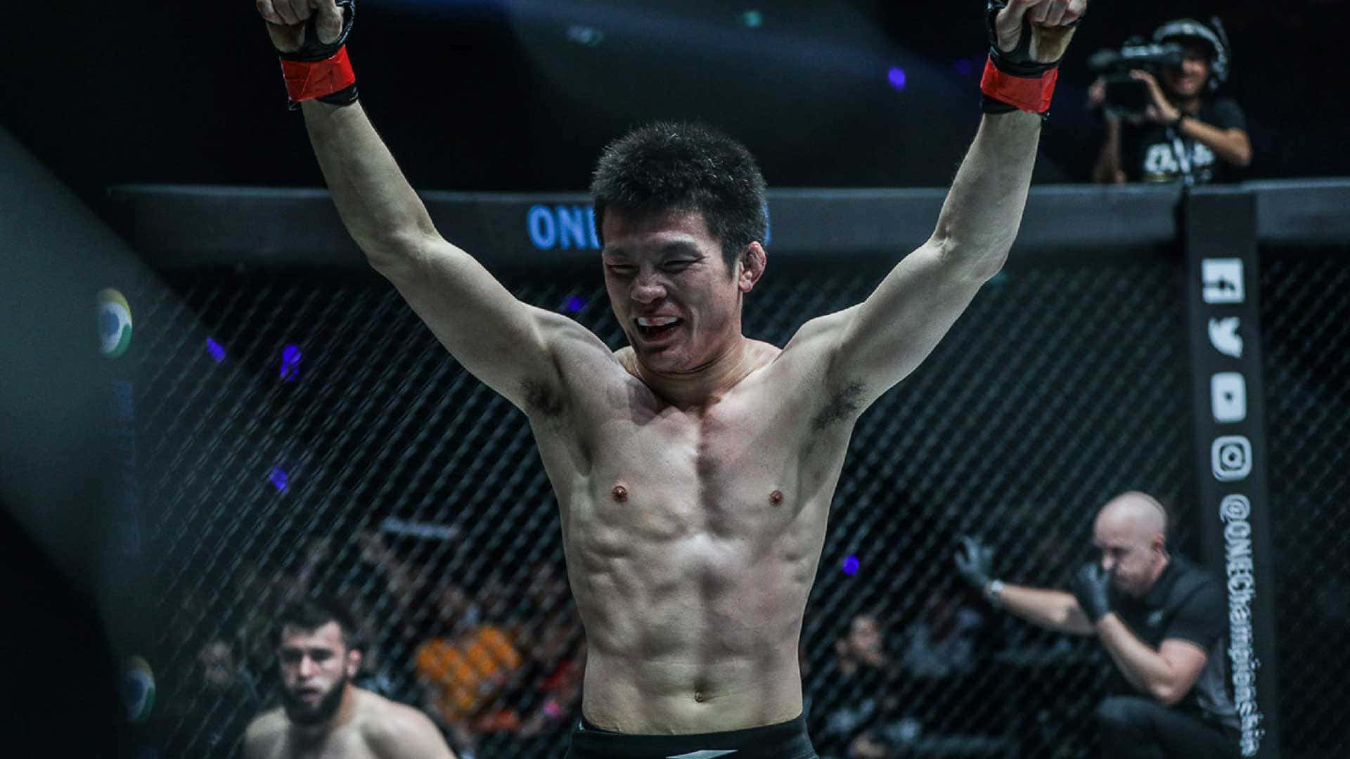 MMA 選手在八角籠中舉臂慶祝勝利。