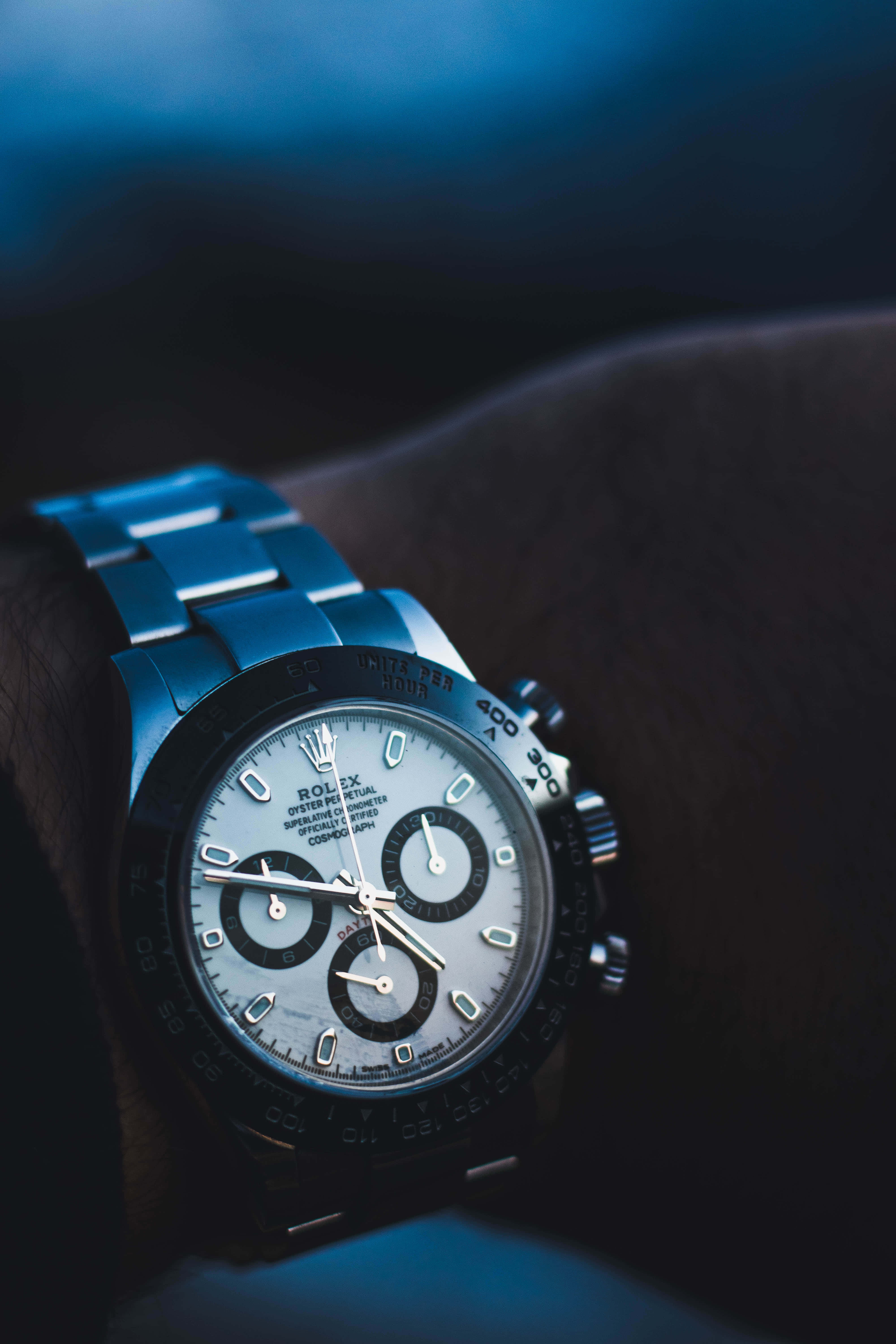 Rolex 桌布 壁紙 — 勞力士Daytona手錶戴在手腕上的特寫，帶有藍色燈光和模糊背景。