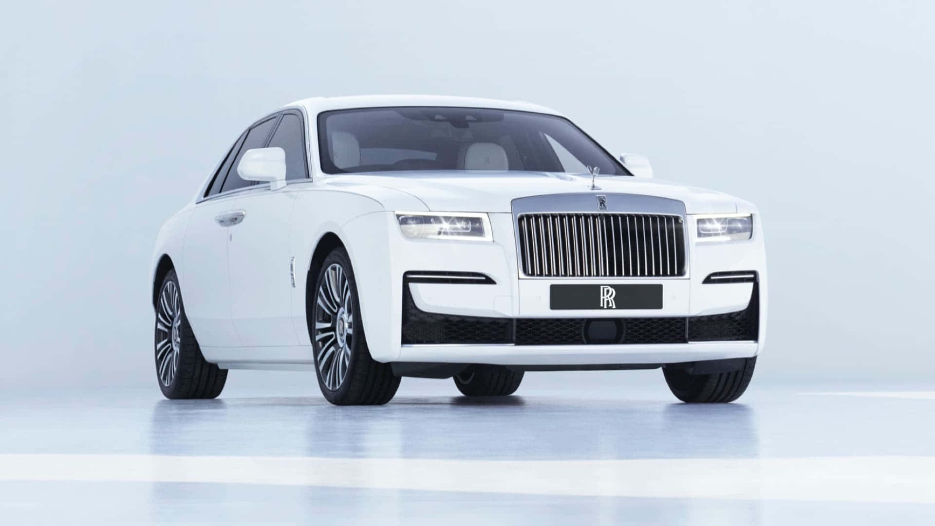 一輛白色勞斯萊斯 Ghost 豪華轎車在簡約的工作室環境中。