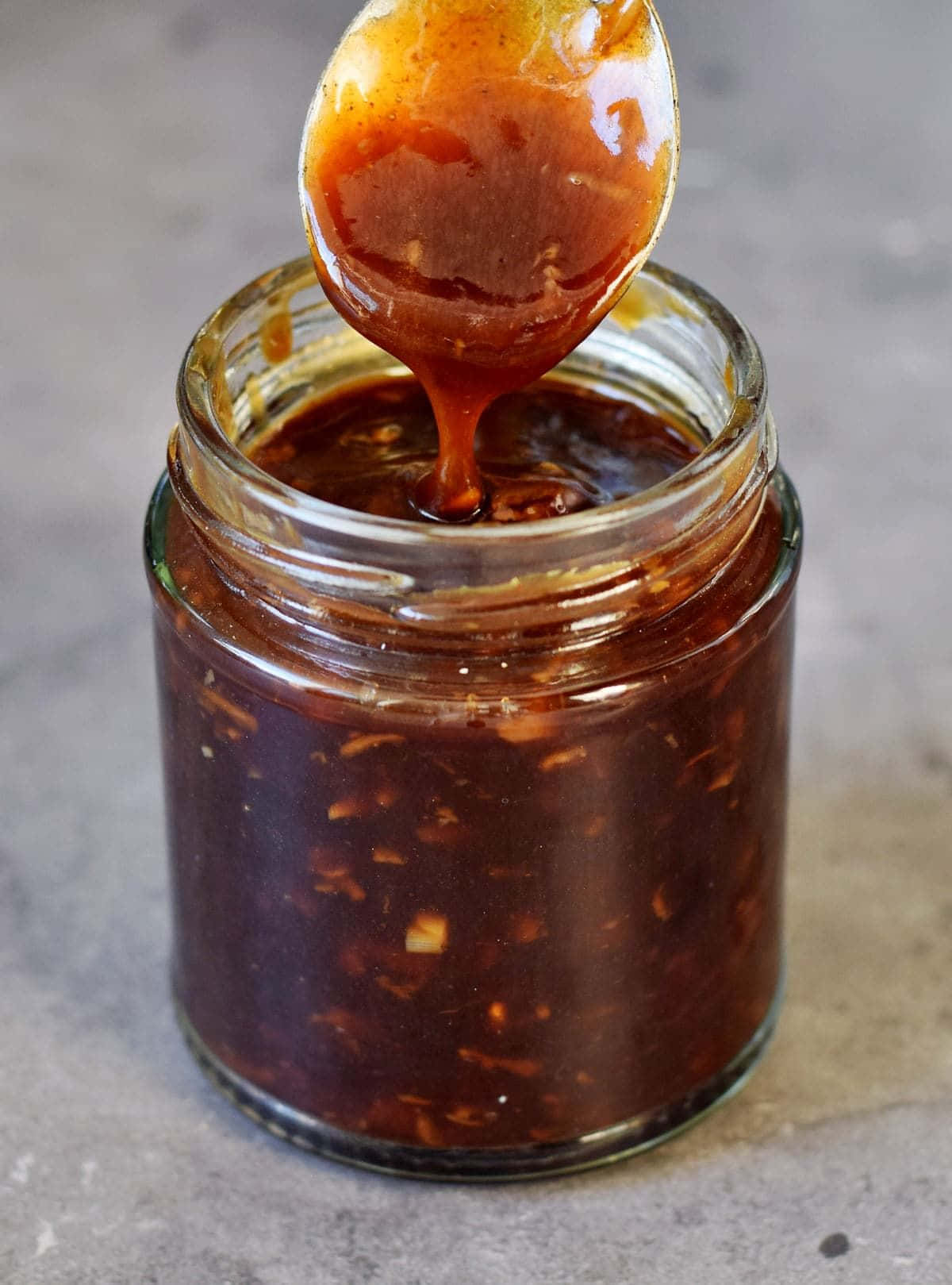 Szechuan Sauce 桌布 壁紙 — 勺子從玻璃罐中舀起濃稠光澤的燒烤醬，展現出塊狀質地和豐富的琥珀色。