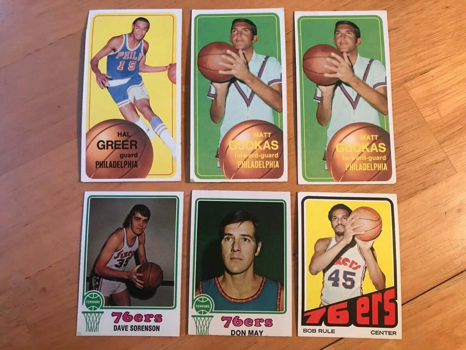 六張1970年代費城76人隊復古籃球交易卡在木地板上。