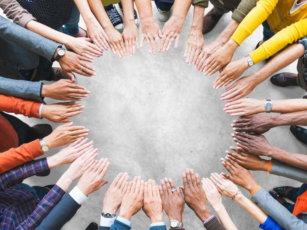 多種手在混凝土地板上形成一個圓圈，象徵團結與協作。