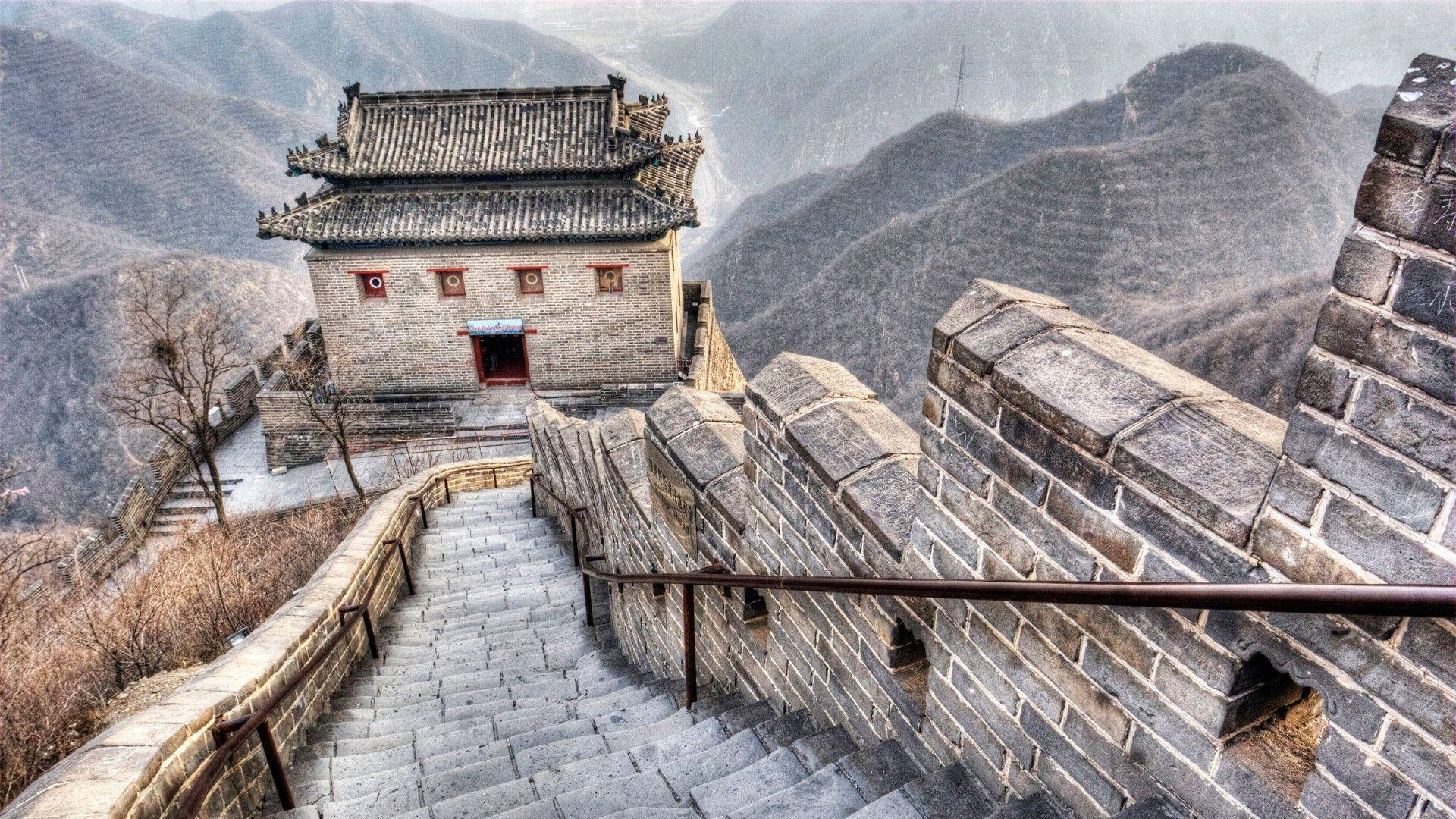石階通往長城上的一座歷史瞭望塔，周圍是霧氣繚繞的山巒。