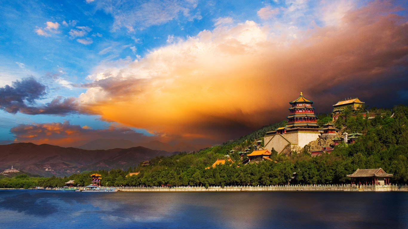 山坡上的一座寶塔在日落時分倒映在湖中，天空佈滿戲劇性的雲彩。