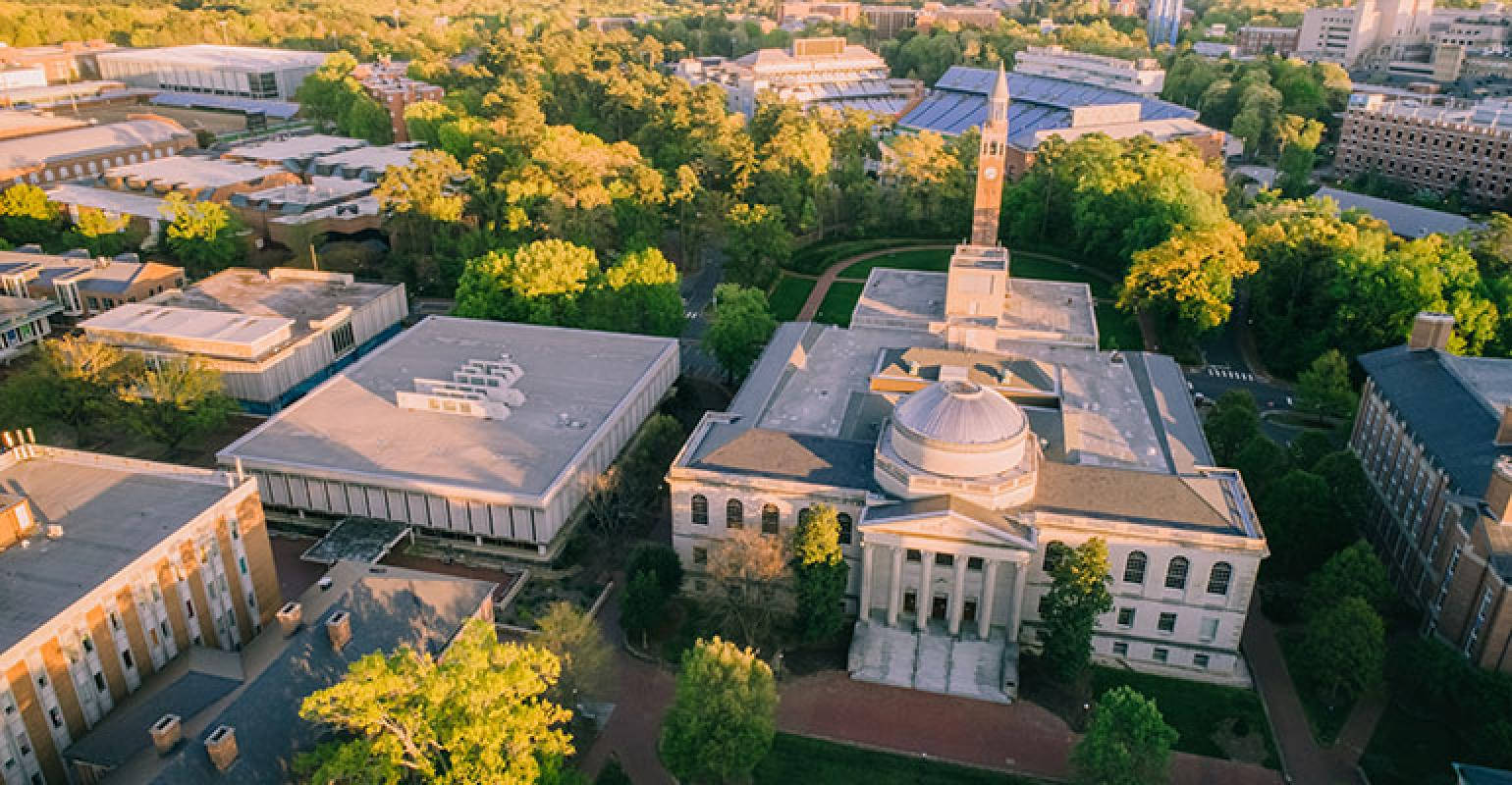 大學校園的鳥瞰圖，古典建築和綠色樹木在金色陽光下。
