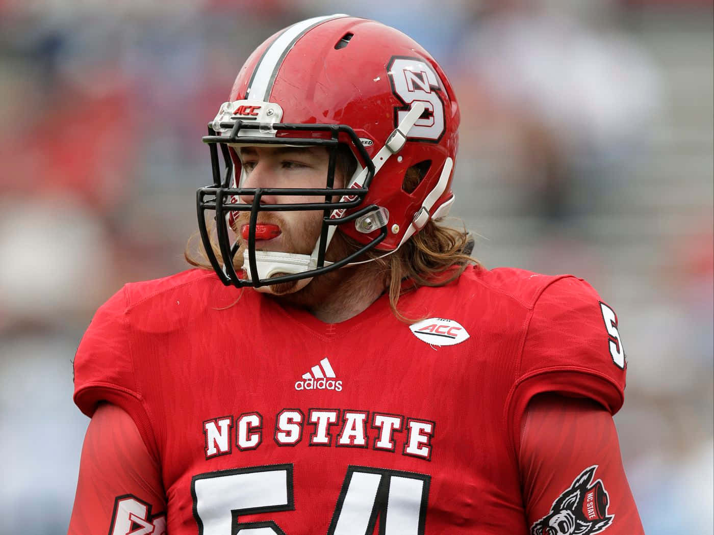 身穿紅色制服、戴頭盔、留長髮的NC State美式足球員。