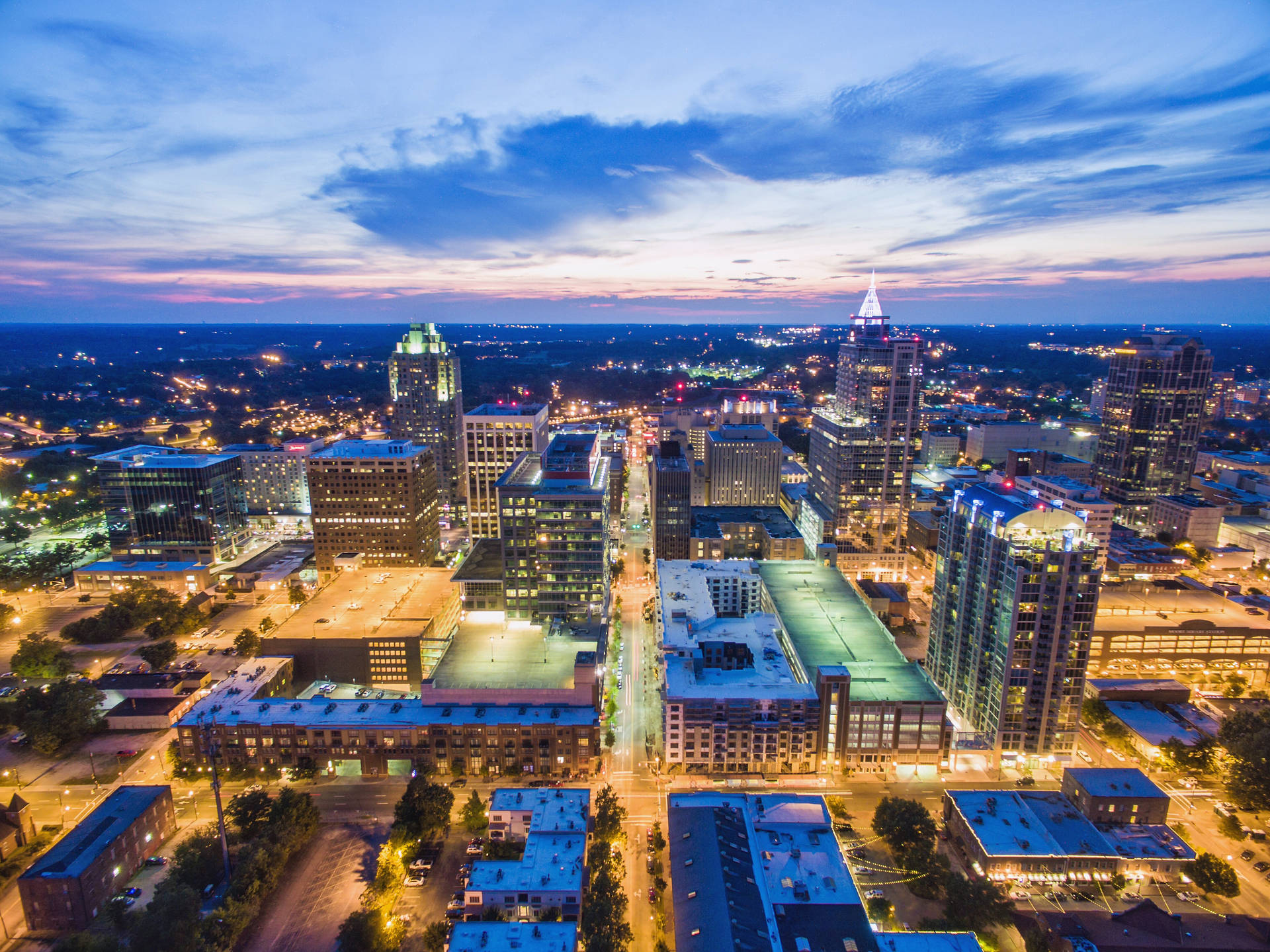 黃昏時分的城市天際線，在色彩繽紛的天空下，建築物和街道閃閃發光。