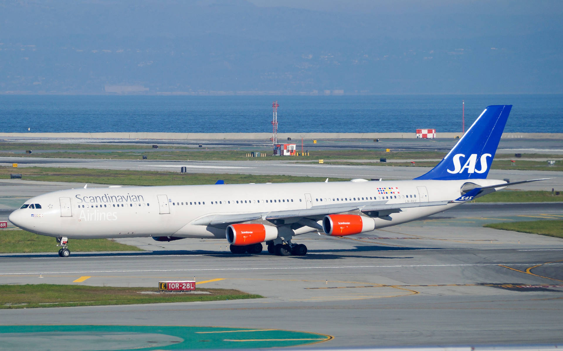 北歐航空空中巴士A330在跑道近海洋，背景有山