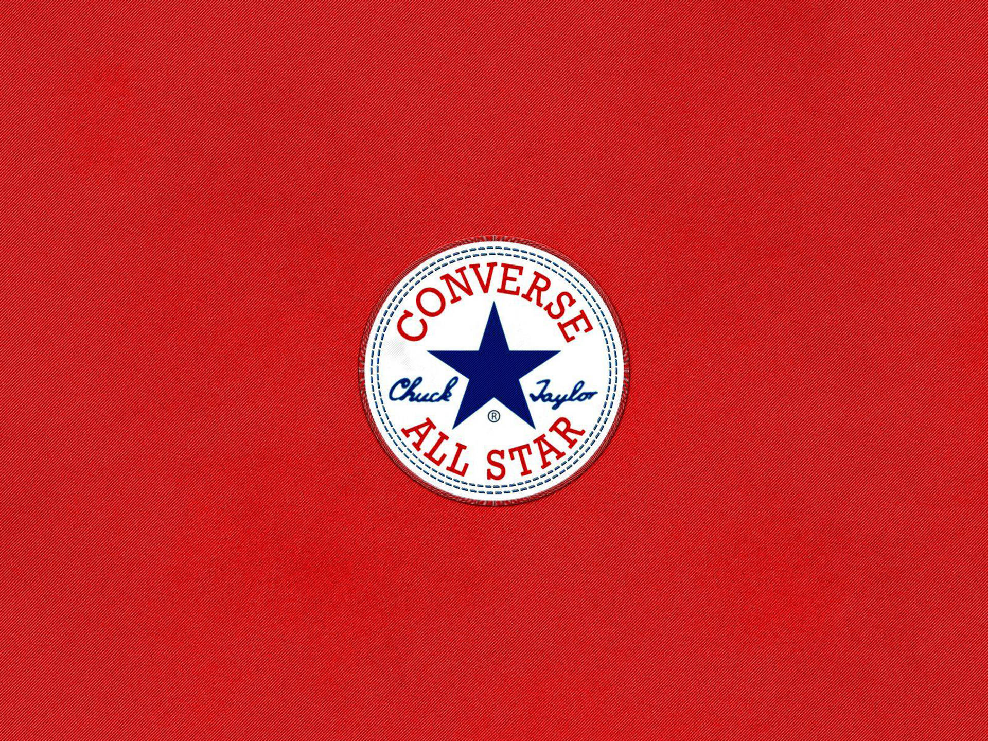 匡威標誌紅色背景 壁紙 — 經典Converse Chuck Taylor All Star標誌置於有紋理的紅色布料背景中央。