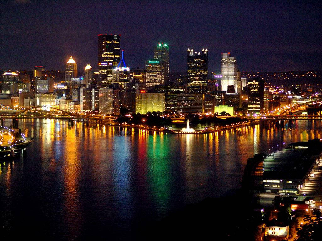 夜間城市天際線，燈火通明的建築物和河流倒影。