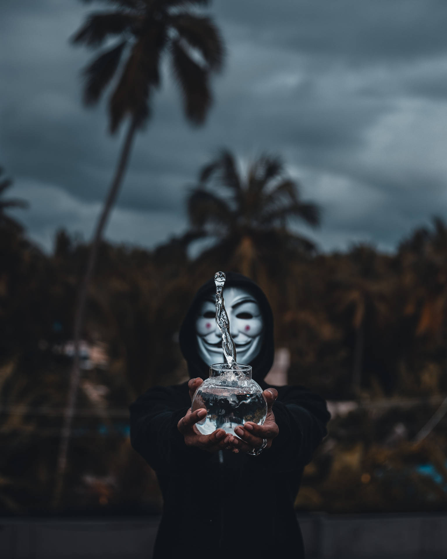 匿名人物在暴風雨的天空下，手持玻璃碗，水從勺子滴落。