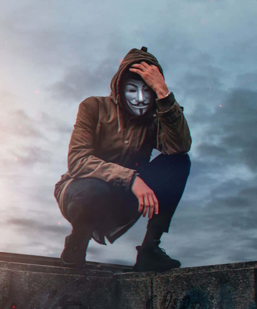 戴著蓋伊·福克斯面具的人蹲在混凝土邊緣上，黃昏時分。