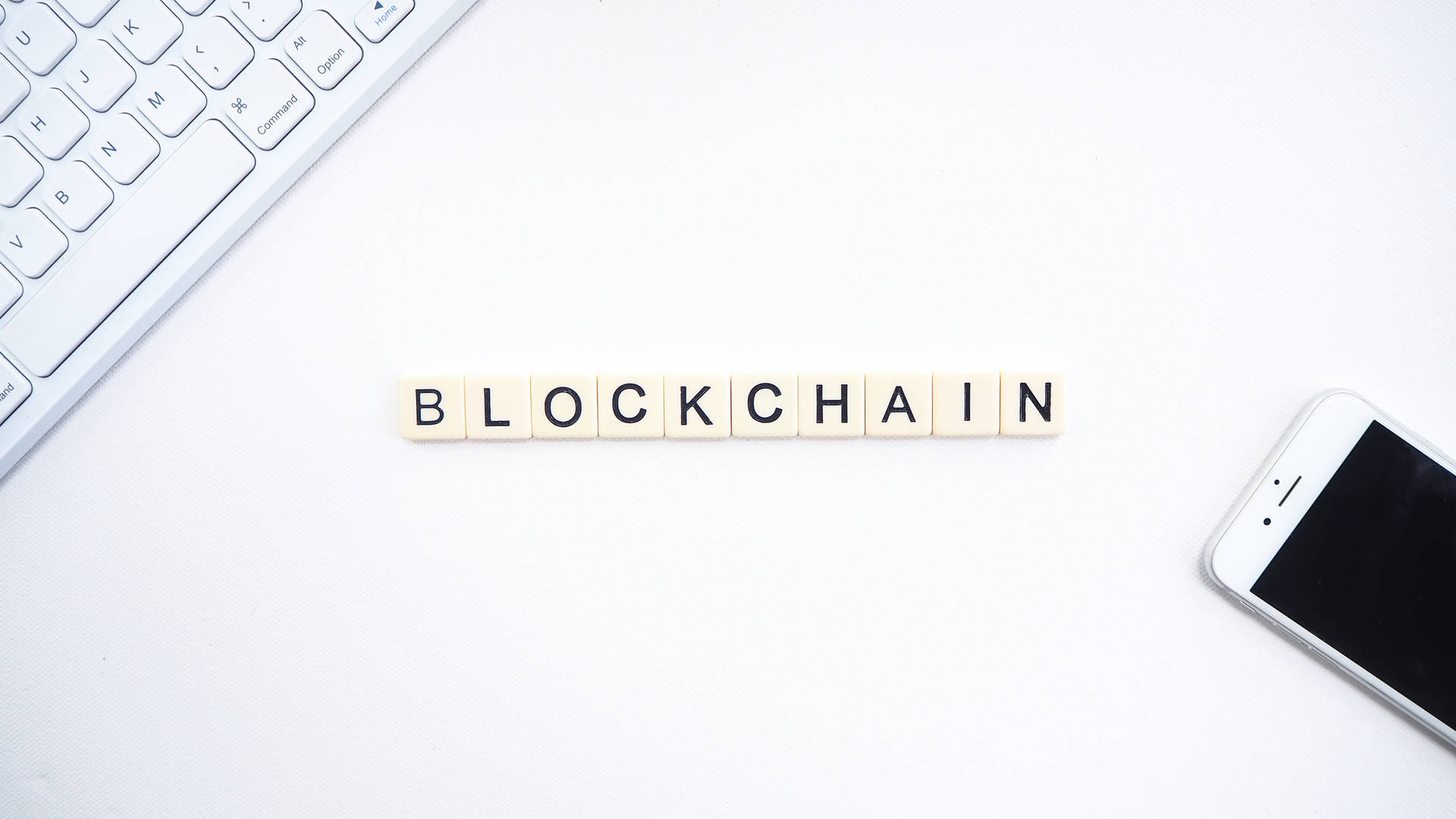 白色辦公桌上，用木製瓷磚拼出blockchain，旁邊有鍵盤和電話。