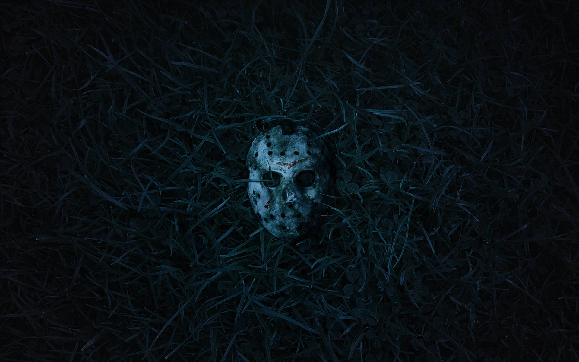 一個血淋淋的曲棍球面具在夜間躺在黑暗的草地上。