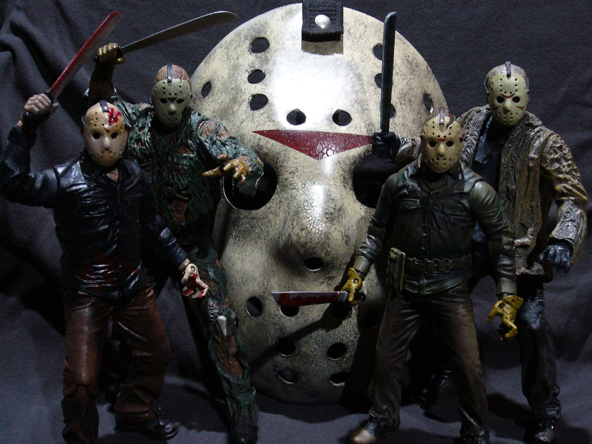 四個 Jason Voorhees 動作人偶，拿著刀和面具，圍繞一個巨大的曲棍球面具。