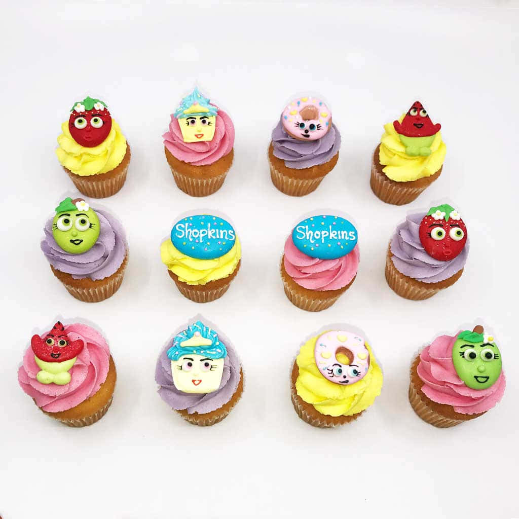 Shopkins 桌布 壁紙 — 十二個色彩繽紛的杯子蛋糕，上面有可愛的Shopkins角色，放在潔淨的白色背景上。