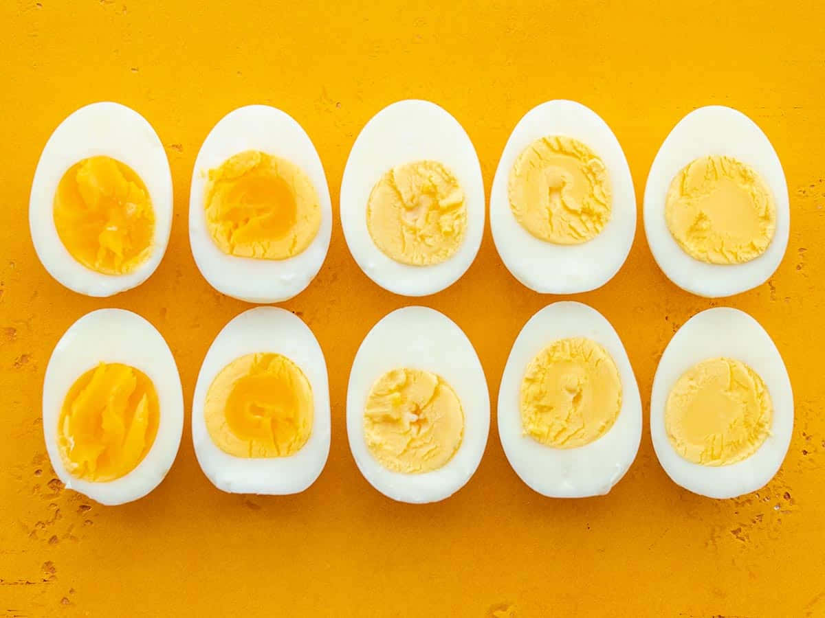 Egg 桌布 壁紙 — 十個半邊水煮蛋整齊排列在充滿活力的橙色紋理表面上。