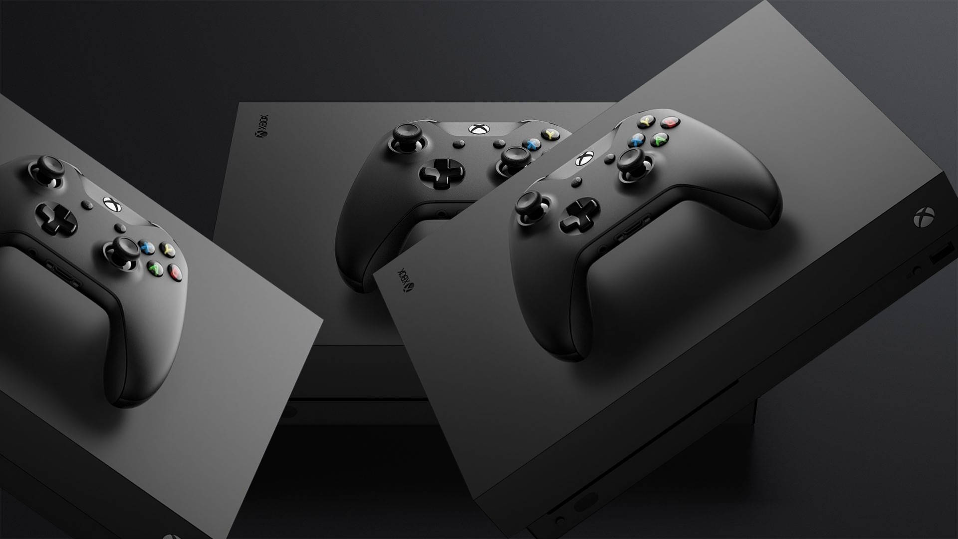 在黑暗的攝影棚環境中，三個黑色Xbox控制器放在主機盒上。