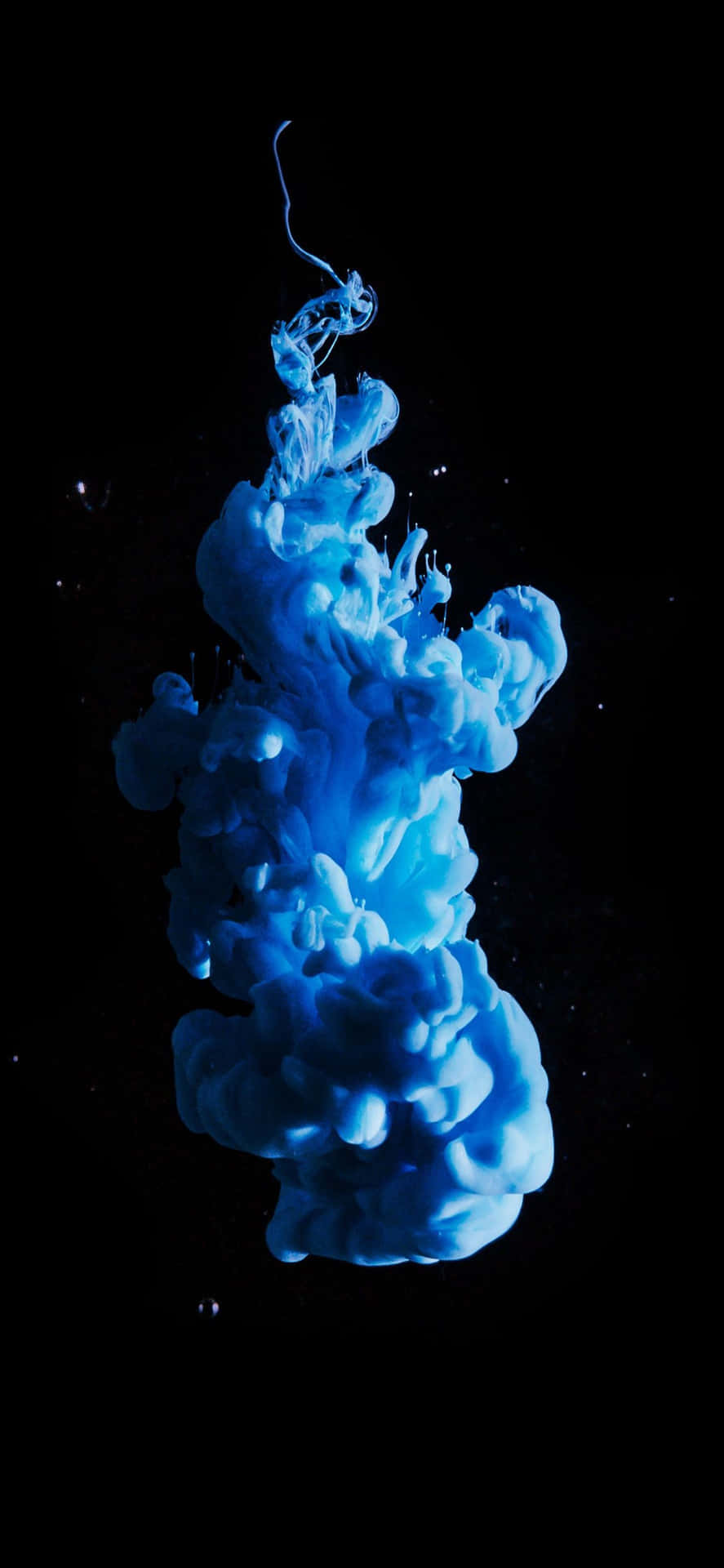 藍色墨水在水中旋轉，背景為黑色