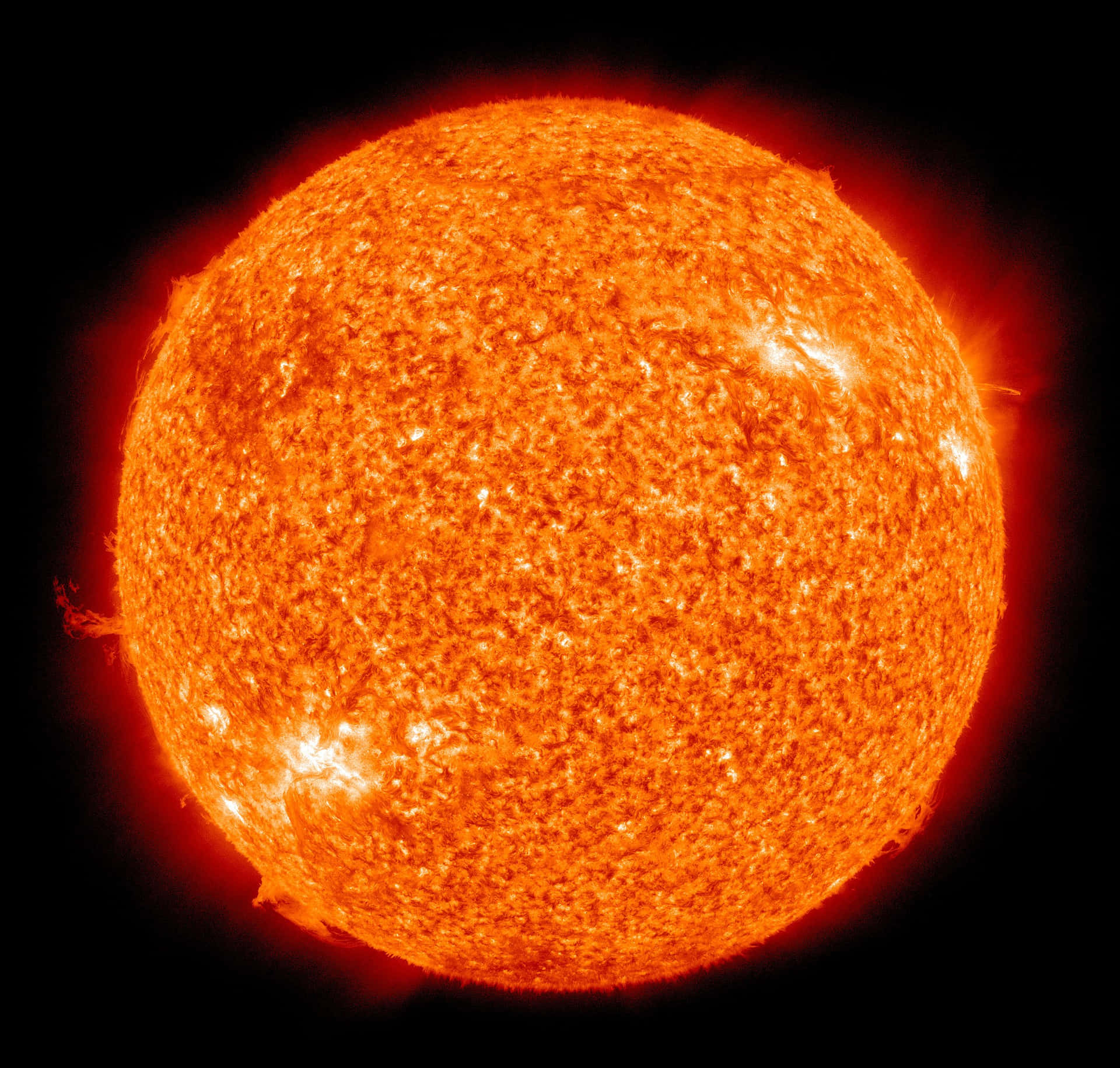 一顆發光的橙色太陽，帶有太陽耀斑，背景為黑色。