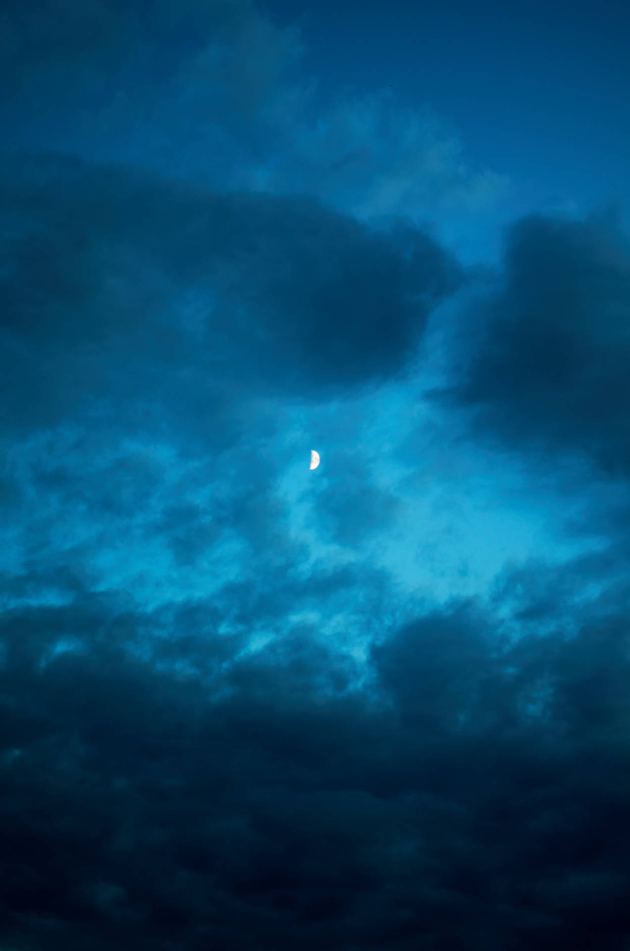 月牙在深藍色夜空中穿過烏雲閃耀