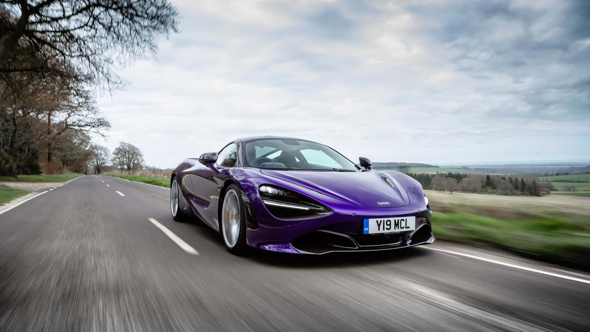 紫色McLaren 720S在鄉村道路上疾馳，背景模糊。