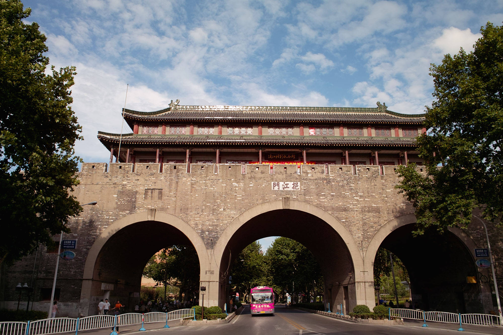南京儀江門 壁紙 — 一座宏偉的傳統中國城門，有三個拱門，矗立在點綴著蓬鬆白雲的明亮藍天下。