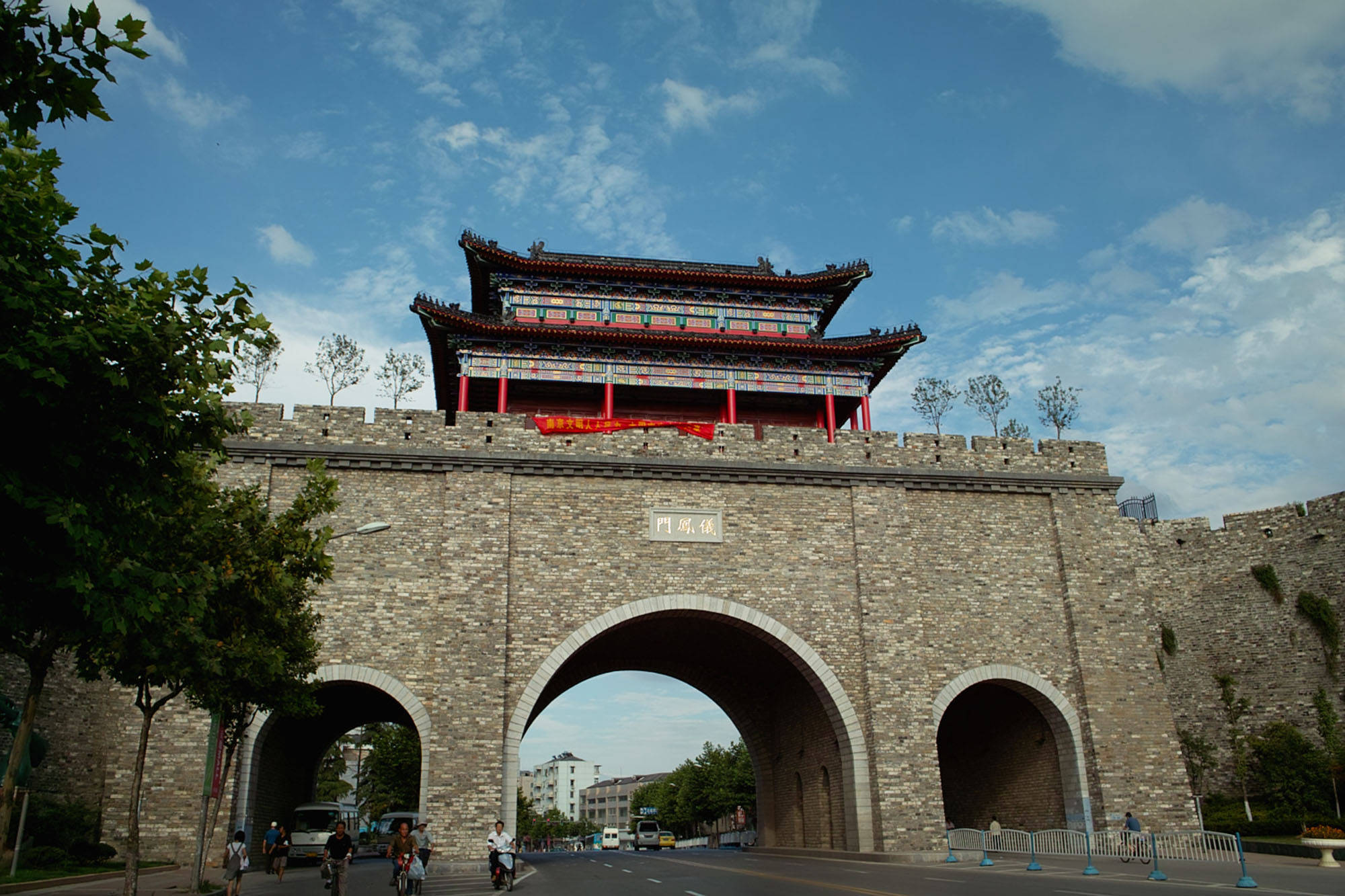 南京御風門 壁紙 — 一座宏偉的傳統中國城門，紅柱和瓦頂在藍天白雲下巍然聳立。