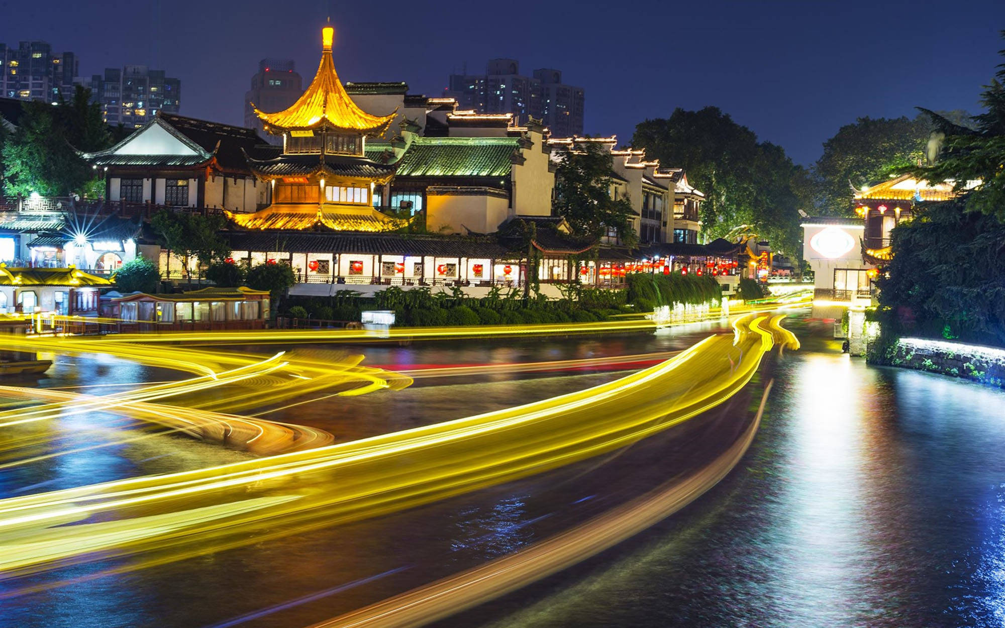 南京秦淮河 壁紙 — 金色光跡在夜晚濕漉漉的街道上劃過，下方是燈火輝煌的傳統中式建築。