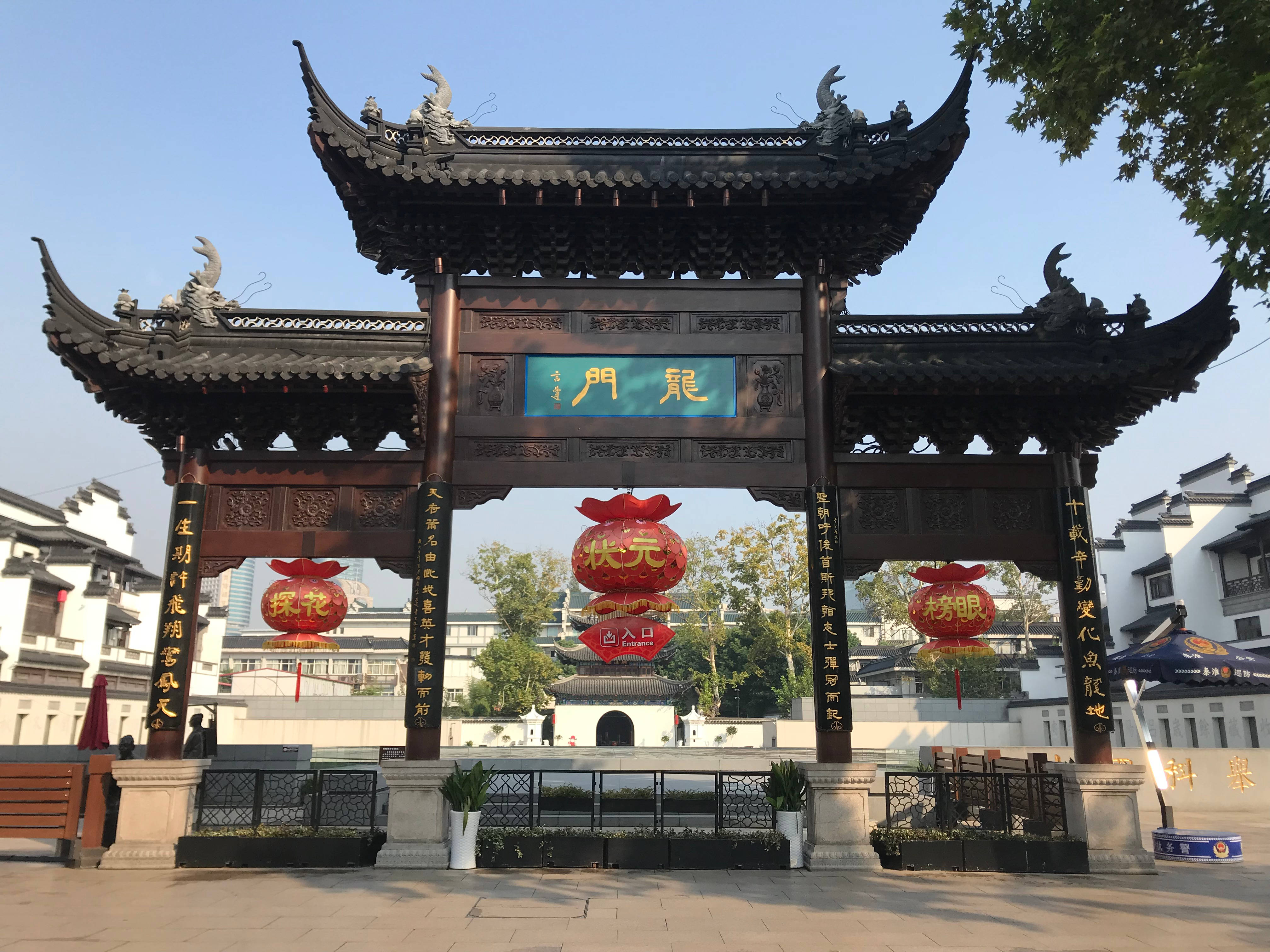 南京老東門 壁紙 — 傳統中式門樓，帶有彎曲的屋檐和紅色燈籠，矗立在歷史城鎮廣場的藍天白雲下。