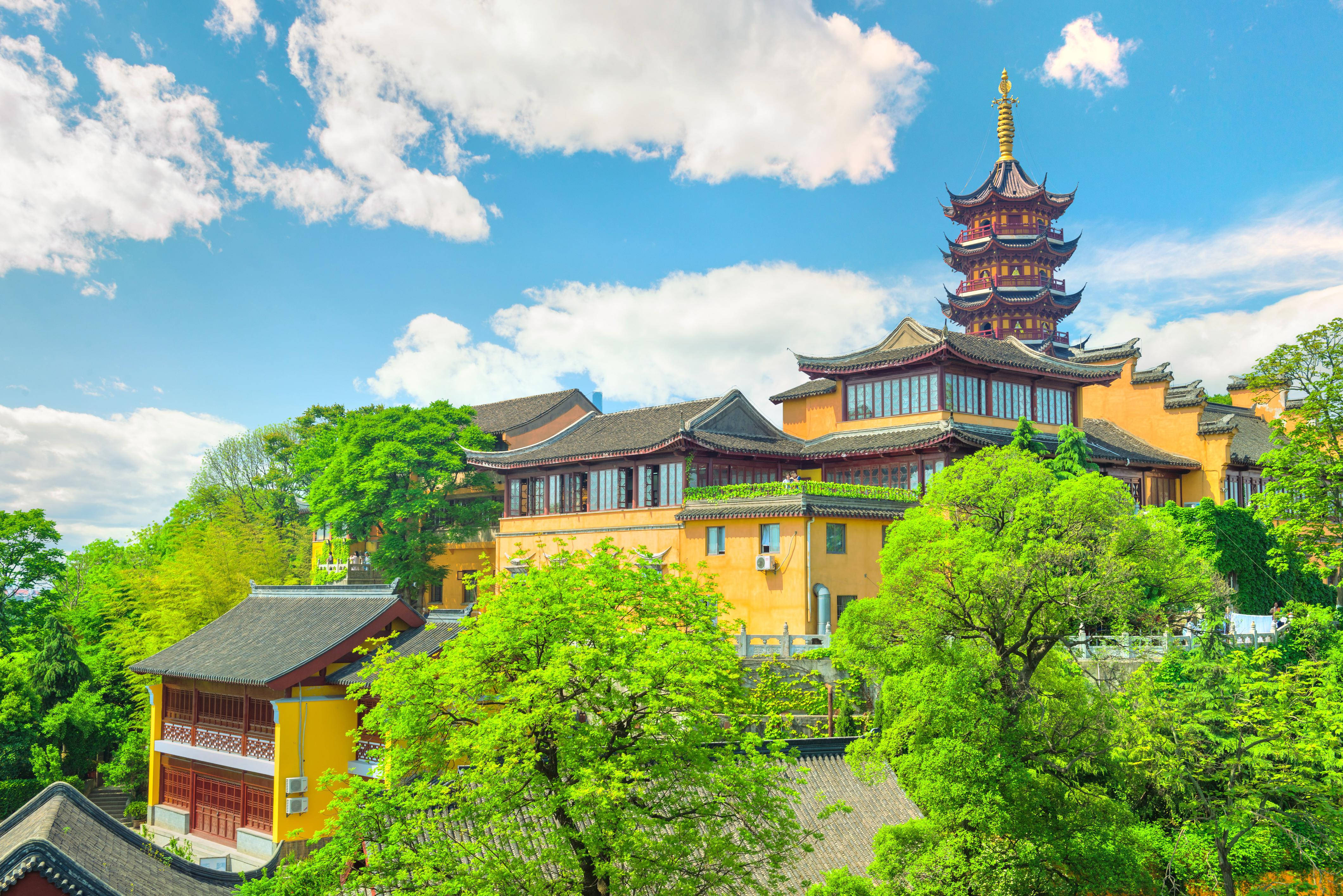 南京靜明寺 壁紙 — 一座充滿活力的黃色寶塔和寺廟建築群，坐落在茂密的綠樹之中，上方是晴朗的藍天和蓬鬆的白雲。