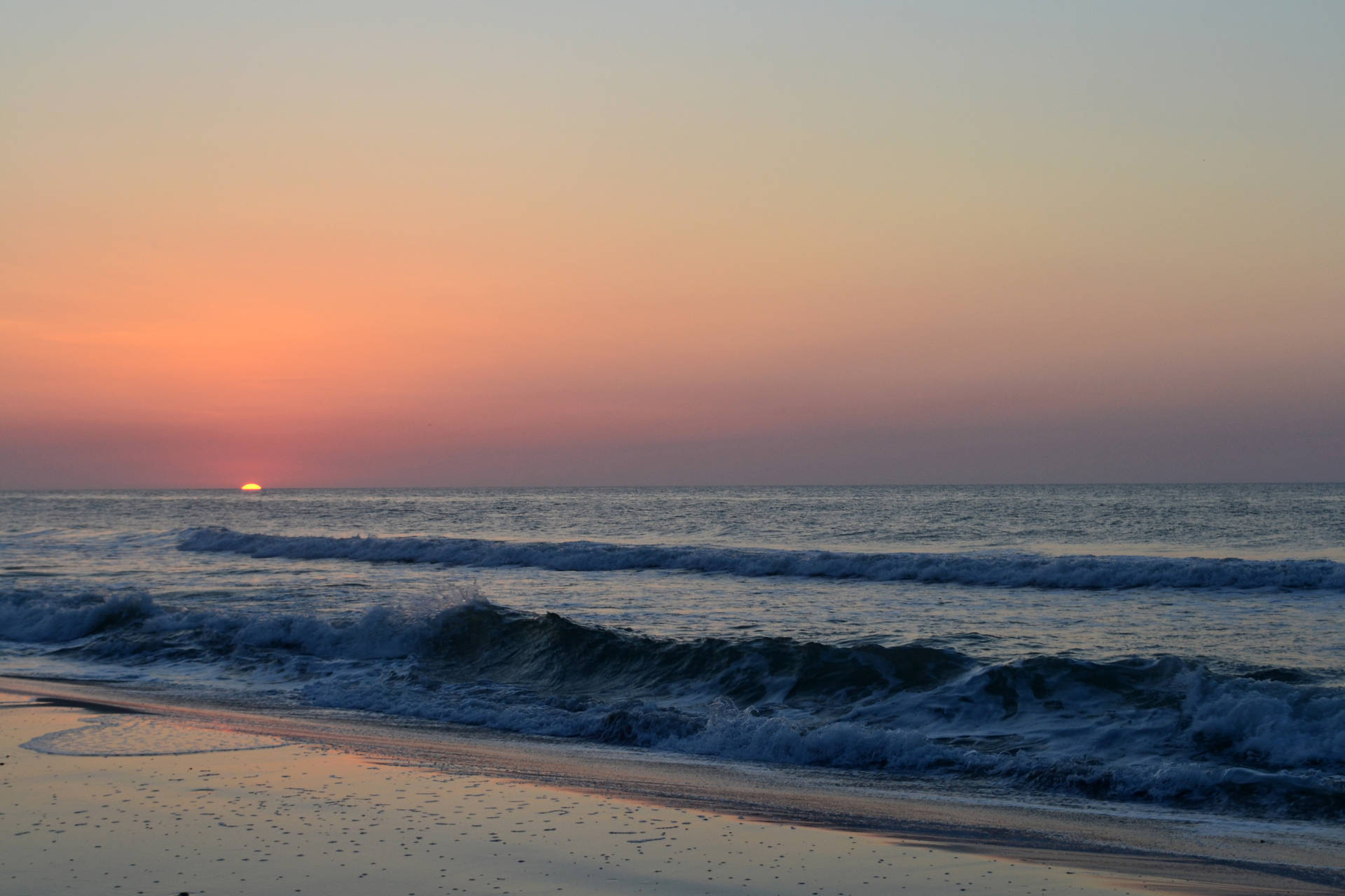 夕陽下的海洋，海浪拍打沙灘