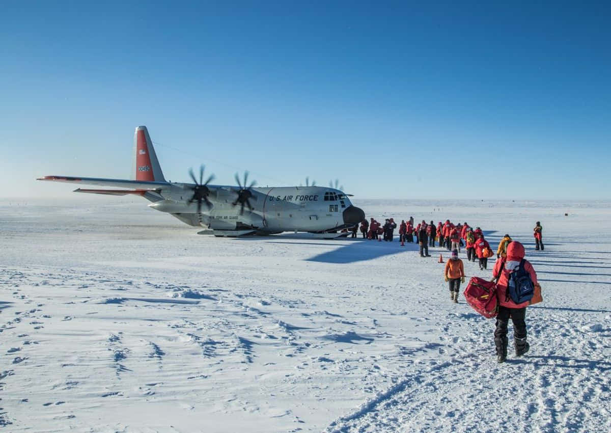 身穿紅色裝備的人們在雪原上走向一架美國空軍飛機。