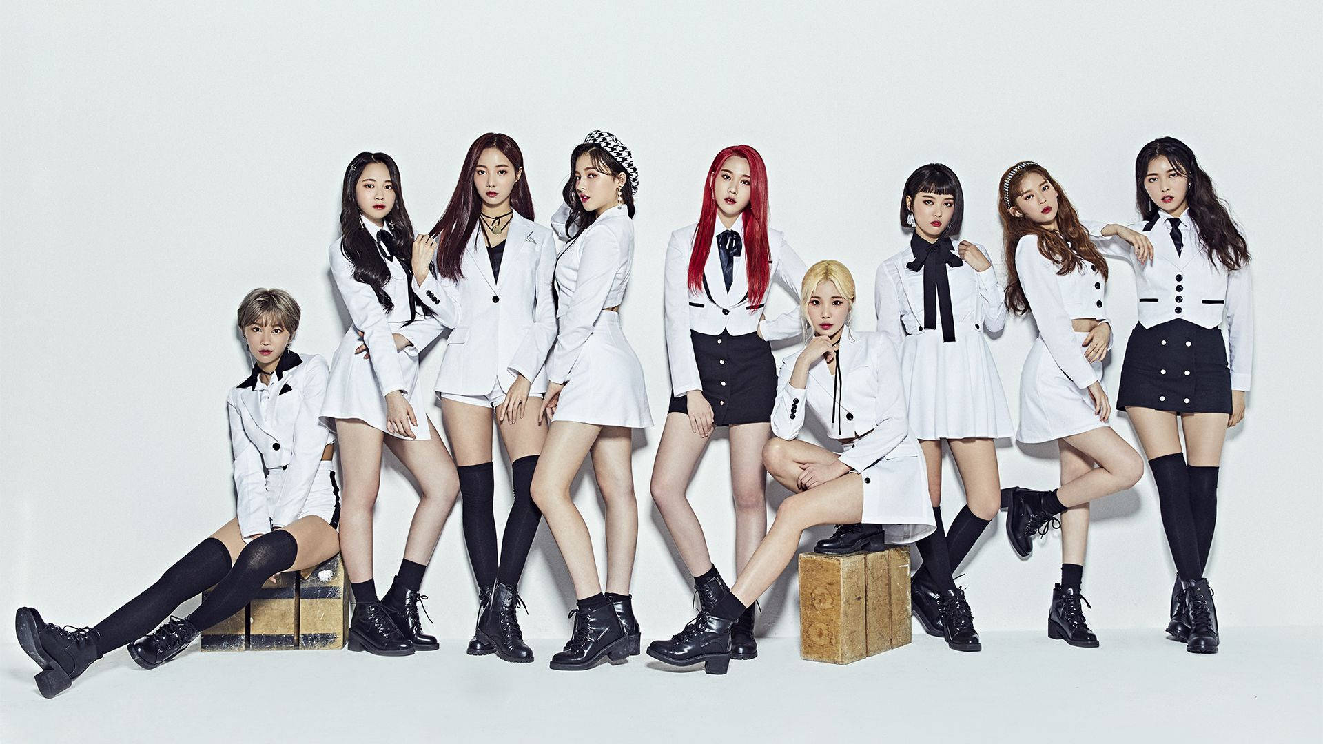 南西 Momoland 黑白高畫質影像 壁紙 — 九位時尚女性穿著相配的白色西裝外套和黑色裙子，在純白色背景前自信地擺姿勢。