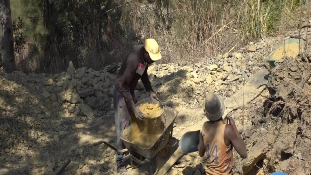 兩名建築工人在戶外將混凝土混合在獨輪車中。