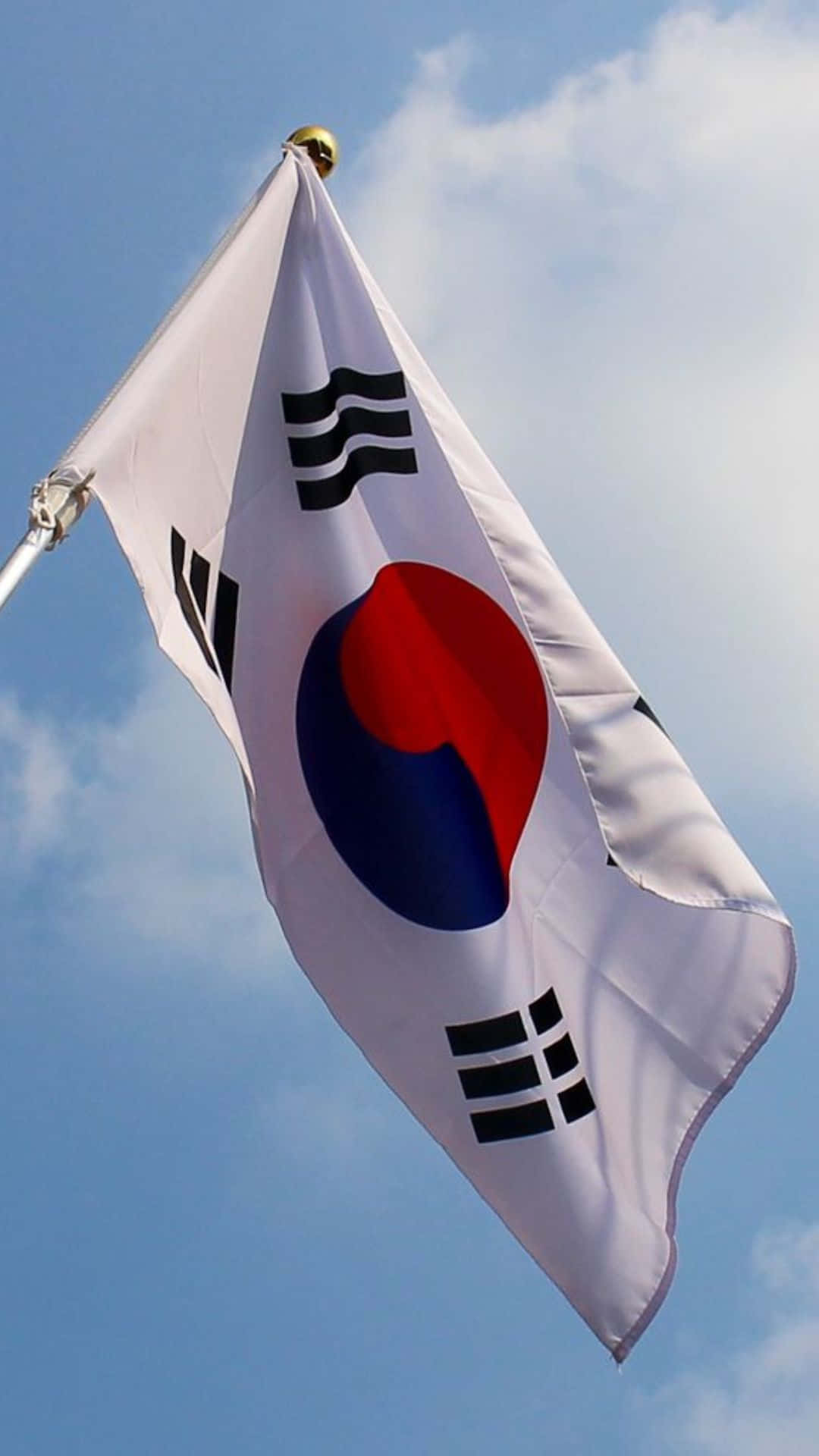 South Korea 桌布 壁紙 — 南韓國旗在晴朗藍天與散落白雲中動態飄揚。