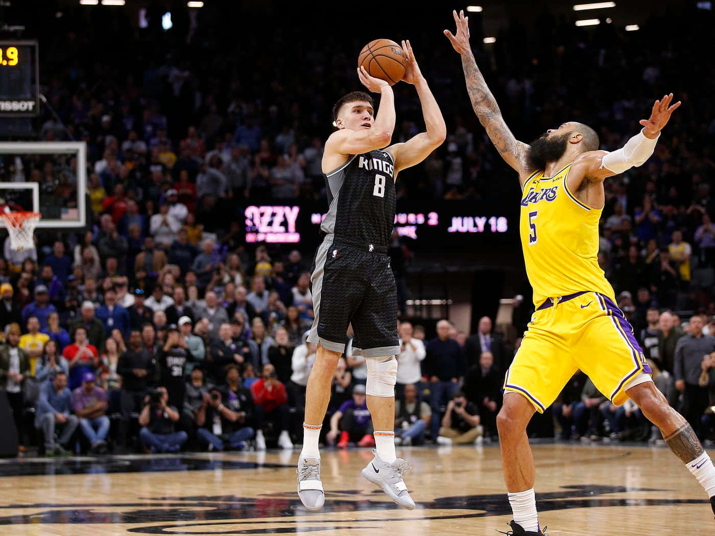 博格丹·博格丹諾維奇投籃訓練對抗馬刺 壁紙 — 一名身穿黑色球衣的籃球運動員跳起投籃，而一名身穿黃色球衣的防守球員試圖封阻。