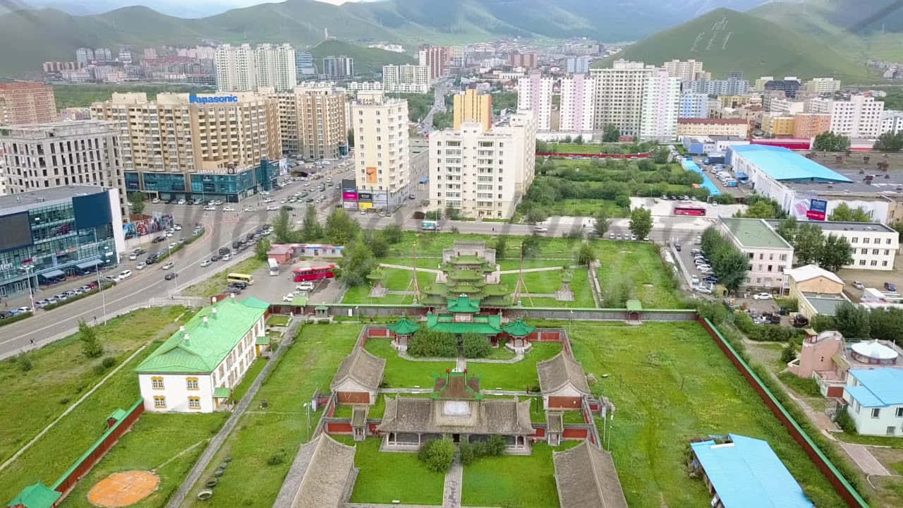 從高空俯瞰城市，現代建築與被綠意環繞的傳統寺廟。