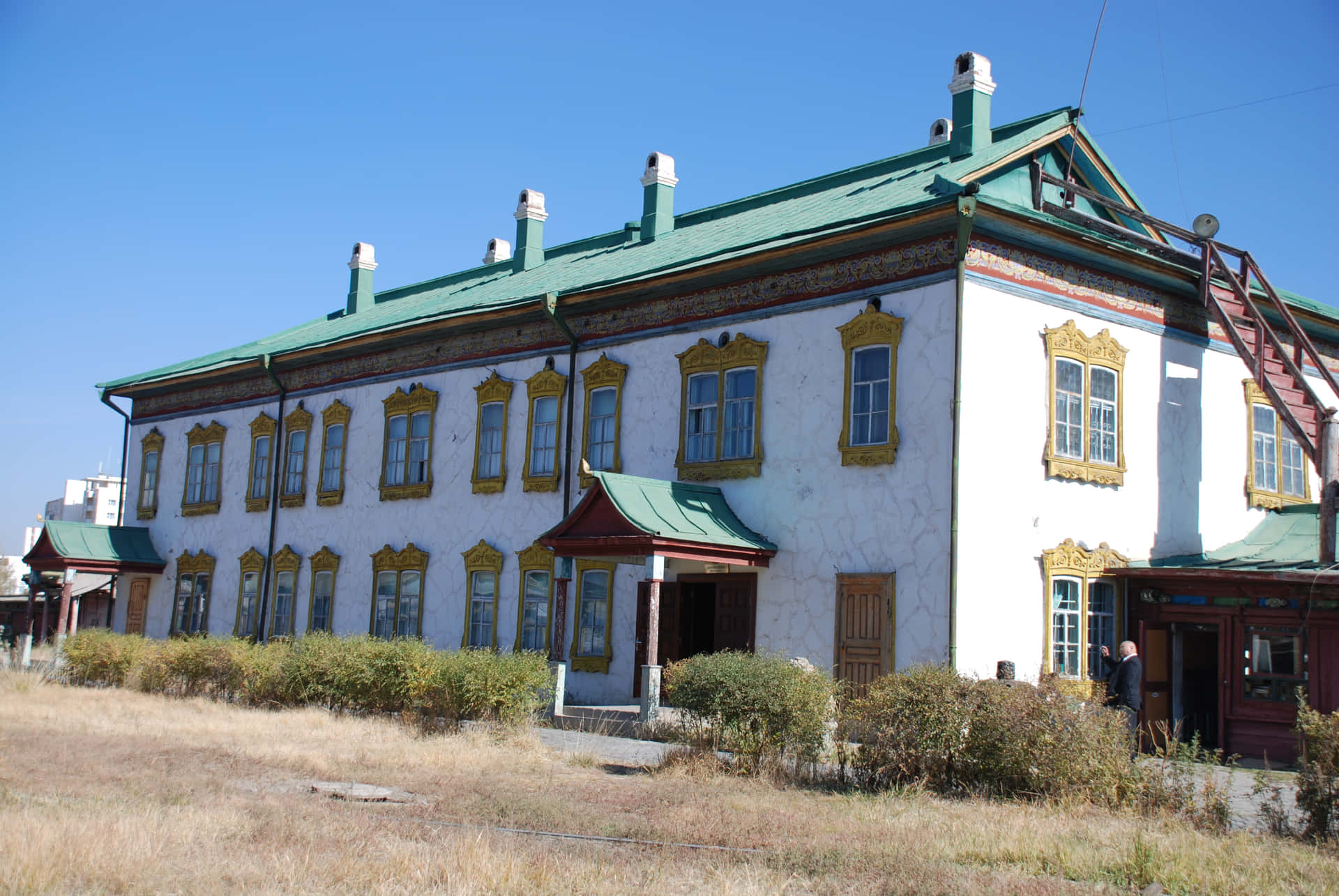 歷史悠久的白色建築，帶金色裝飾和綠色屋頂，陽光明媚