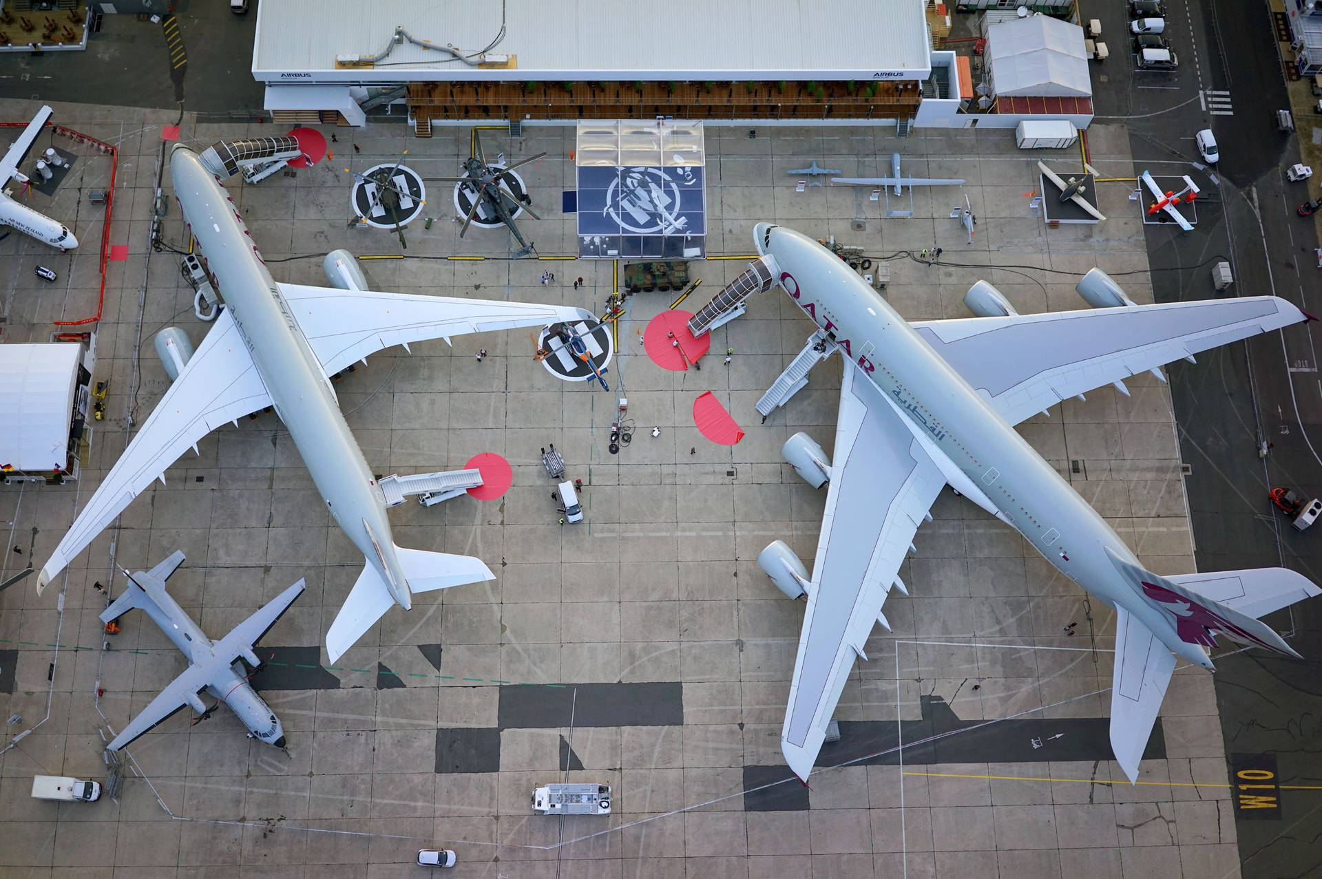 兩架卡塔爾航空飛機停泊在機場停機坪，有地勤人員和車輛。