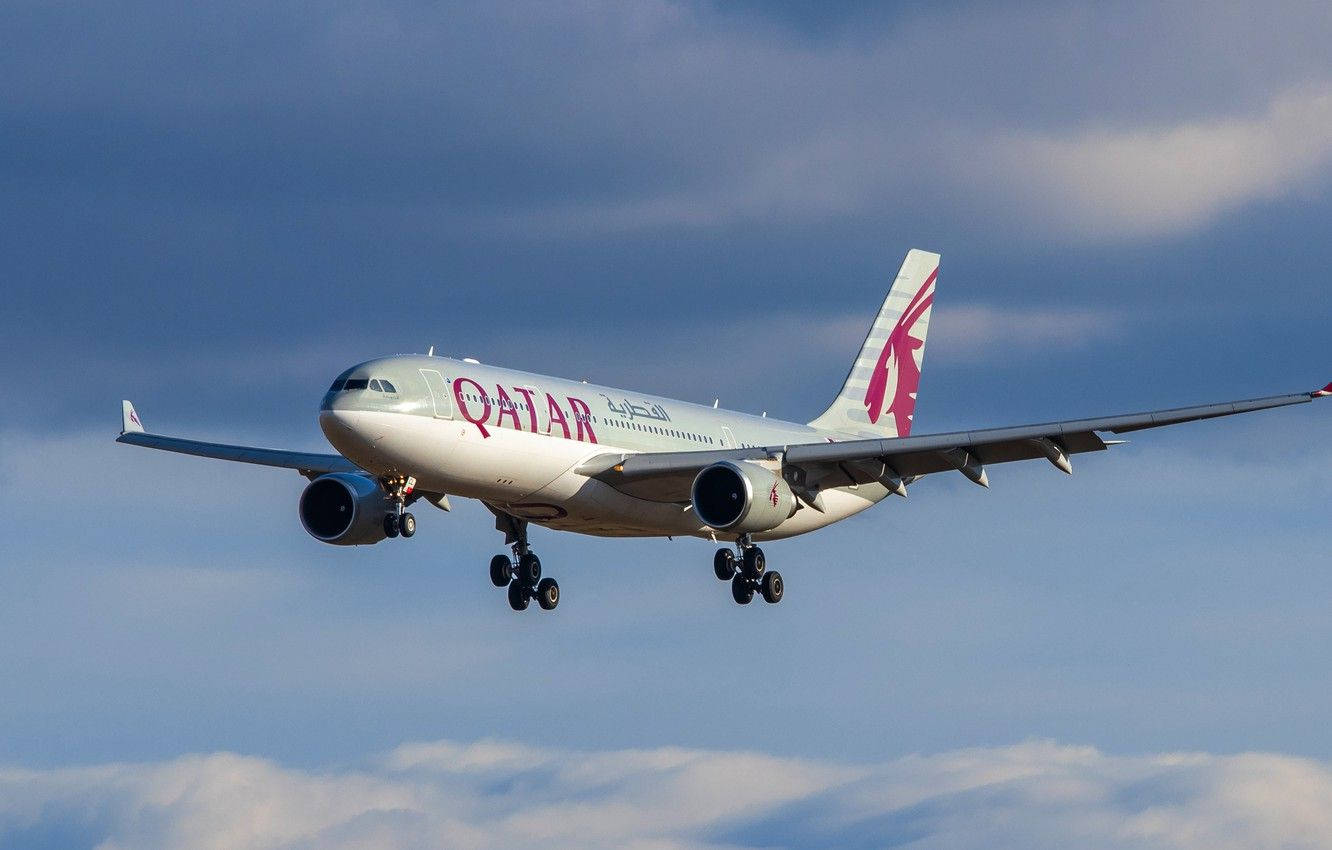 卡塔爾航空飛機在藍天白雲下放下起落架降落
