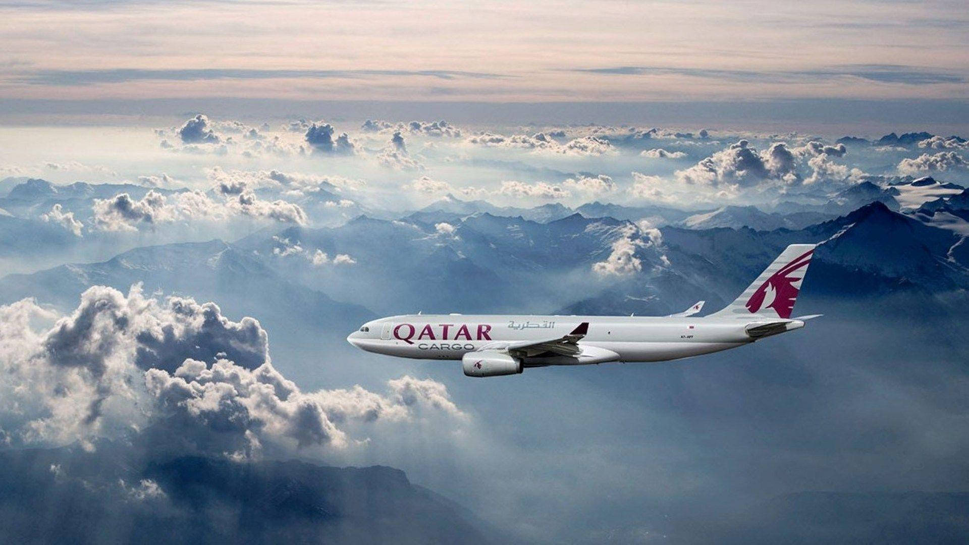 卡塔爾航空飛機藍天 壁紙 — 卡塔爾航空貨機在雲海上翱翔，下方可見積雪覆蓋的山脈。