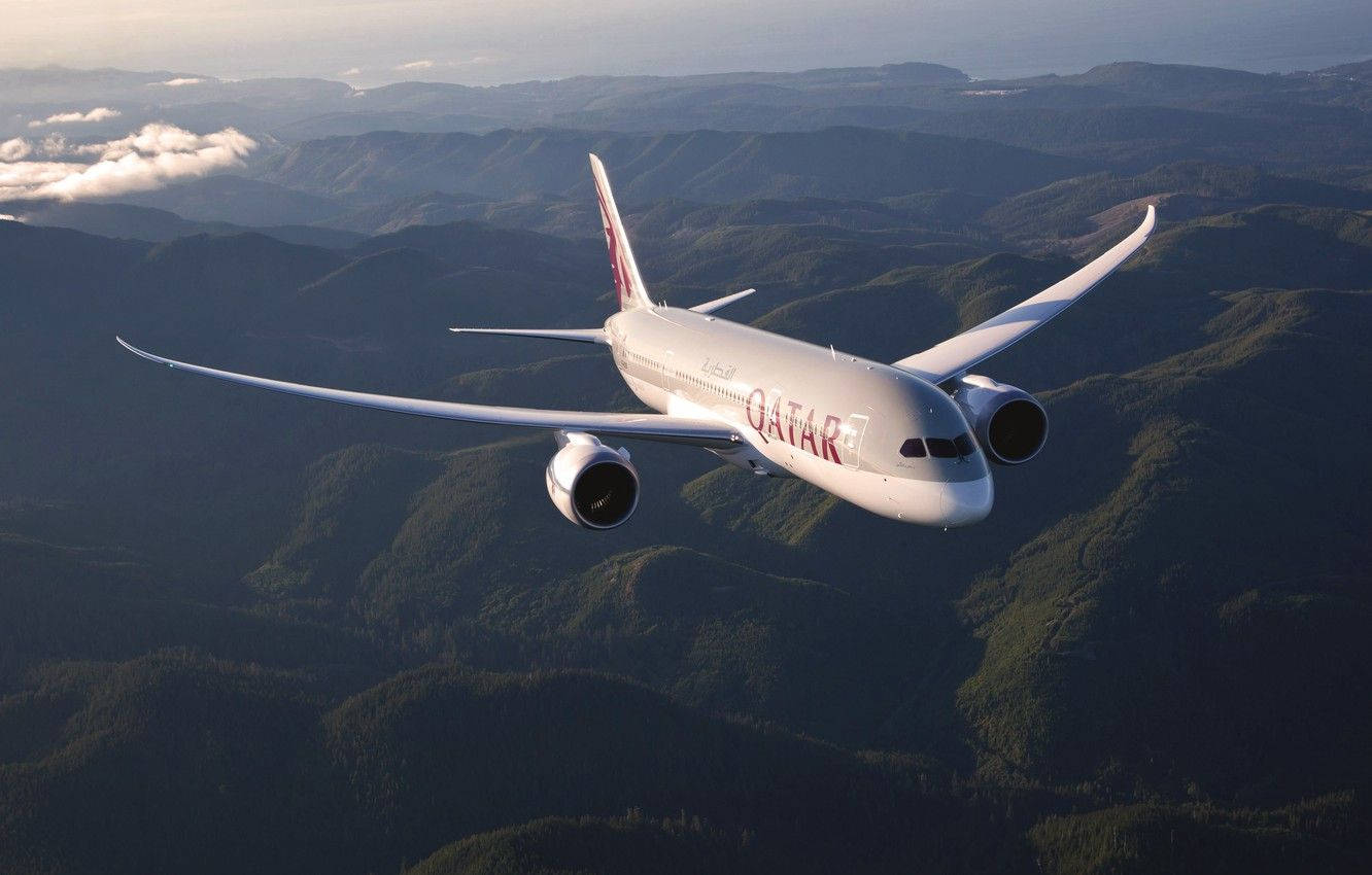 卡塔爾航空飛機在日落時分飛越綠色山脈