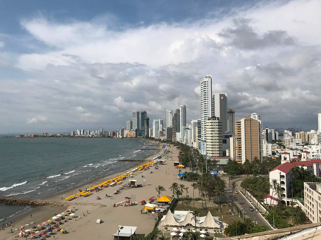 多雲天空下的沿海城市，有沙灘遮陽傘和高樓大廈