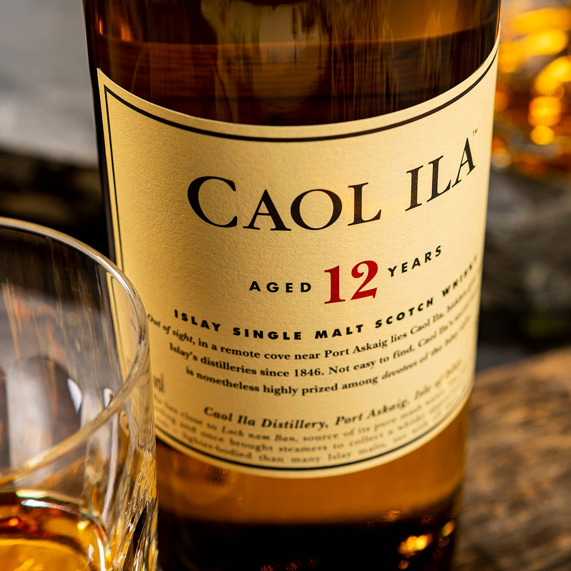 Caol Ila 12年威士忌酒瓶和玻璃杯放在木桌上。